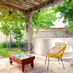 An outdoor patio with a glass-top table, two chairs, a pergola, and a stone wall. - Casa Diamante : 4 Bedrooms + Private Swimming Pool and 2 Premium Suites (Mérida)