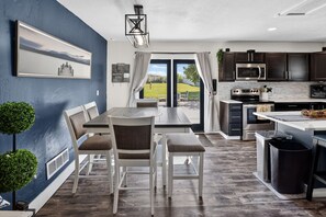 A modern kitchen with dark cabinets, stainless steel appliances, and a dining area with a table and chairs.