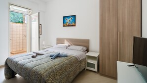 A modern bedroom with a bed, a TV, and a painting on the wall. - Holiday Home 'Lu Sule Lu Mare Lu Ientu1' with Private Garden, Wi-Fi and Air Conditioning (Porto Cesareo)