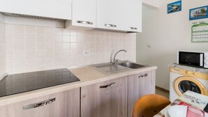 A compact kitchen with a sink, microwave, and a washing machine. - Holiday Home 'Lu Sule Lu Mare Lu Ientu1' with Private Garden, Wi-Fi and Air Conditioning (Porto Cesareo)