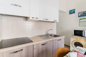 A compact kitchen with a sink, microwave, and a washing machine. - Holiday Home 'Lu Sule Lu Mare Lu Ientu1' with Private Garden, Wi-Fi and Air Conditioning (Porto Cesareo)