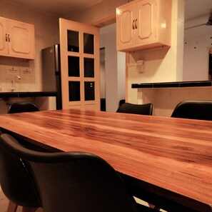 A kitchen with a wooden table, black chairs, and light-colored cabinets.