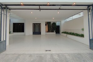 A spacious indoor area with a tiled floor, a metal railing, and a staircase leading to an upper level.