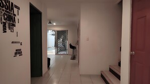 A hallway with a red door, white walls, and a ceiling light.