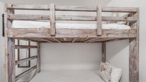 A bunk bed with a wooden frame, white bedding, and a single decorative pillow. - Moonraker 15 (Gulf Shores)