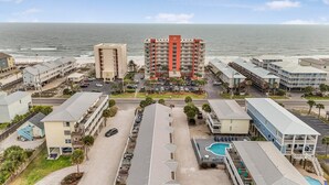 A coastal hotel with multiple buildings, a parking lot, and a pool area. - Moonraker 15 (Gulf Shores)