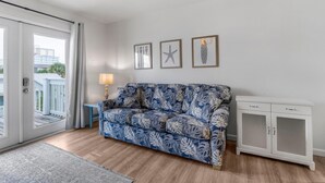 A living room with a blue patterned sofa, a white cabinet, and three framed pictures on the wall. - Moonraker 15 (Gulf Shores)