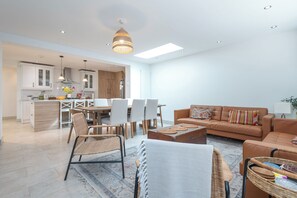 Ein modernes Wohnzimmer mit einer Couch, Sesseln, einem Couchtisch und einem Essbereich mit Tisch und Stühlen.