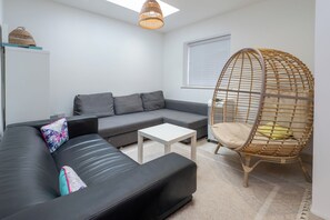 A modern living room with a grey sofa, a white coffee table, and a wicker chair. - Luxurious 3BDR 3BATH Hounslow by the Airport (Greater London)