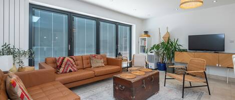 A modern living room with a leather sofa, a wooden coffee table, and a television.