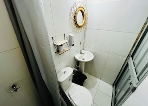 Kylpyhuone, jossa on wc, pesuallas ja suihkuverho.