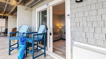 A hotel entrance with a door, a blue chair, a blue umbrella, and a welcome mat.