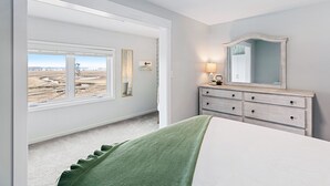 A bedroom with a large window, a dresser, and a mirror. - Twin View: 1 BR, Living Room, Ocean & Marsh Views, Beach Chairs, 1 parking spot (Hampton)