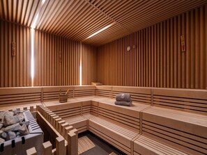 A sauna room with wooden slatted walls, benches, and a stone basin. - 4 Star Holiday Home in Travemunde (Lübeck)
