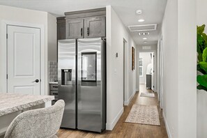 A modern kitchen with a double-door refrigerator, a countertop, and a chair. - Steps to Lake Michigan | Hot Tub + Fire Pit | Near Cave Point (Sturgeon Bay)