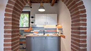 Eine Küche mit einer Ziegelbogenarchitektur, einem Fenster mit dekorativem Gitter und einer modernen Leuchte.