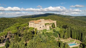 A castle-like structure surrounded by lush greenery and hills. - I Tramonti 10+2, Emma Villas (Montegabbione)