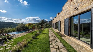 A stone building with a swimming pool, a stone pathway, and a view of the hills. - I Tramonti 10+2, Emma Villas (Montegabbione)