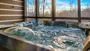 Een hottub met uitzicht op bomen door grote ramen.