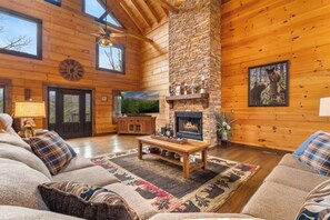 A log cabin interior with a fireplace, wooden walls, a sofa, and a television. - Luxury, Chalet with Private Suite, Secluded, and HotTub (Cosby)