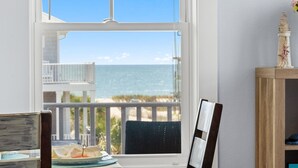 Una stanza con vista sull'oceano, un tavolo da pranzo con piatti e un tavolino in legno con un oggetto decorativo.