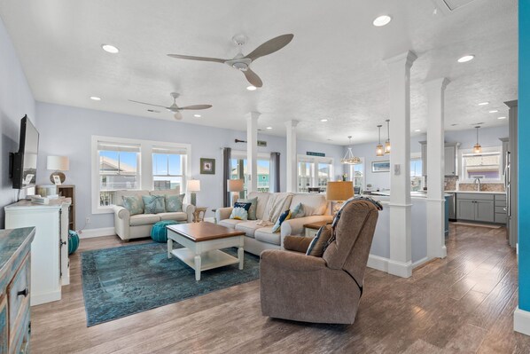 A spacious living room with a sofa, coffee table, and ceiling fans. - See the Ocean, Hear the Waves @ BeeHappy Getaway! Elevator, Heated Pool (Ocean Isle Beach)