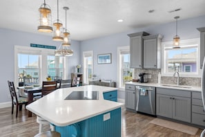 A kitchen with a central island, grey cabinets, and pendant lighting. - See the Ocean, Hear the Waves @ BeeHappy Getaway! NEW Listing! Elevtr, Htd Pool (Ocean Isle Beach)