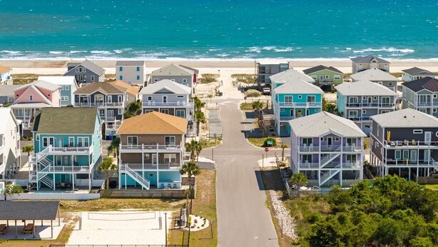 Una zona residenziale sulla costa, con case affacciate sulla spiaggia, un cielo sereno e vista sull'oceano.