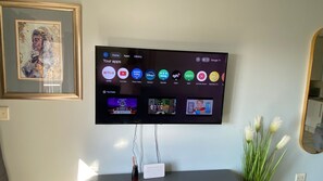Un téléviseur à écran plat fixé au mur, avec une œuvre d’art encadrée au-dessus.