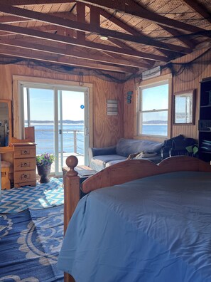 A wooden cabin with a bed, a dresser, and a window overlooking the sea. - Squeeze More Inn on the ocean
Traditional century old Newfoundland home (Lewisporte)