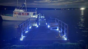 Un muelle se adentra en aguas tranquilas con un barco amarrado a la izquierda.