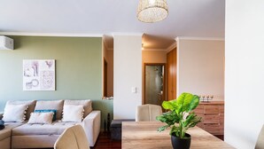 Ein Wohnzimmer mit einer Couch, einem Esstisch mit einer Topfpflanze und einem Flur, der zu einem Badezimmer führt.