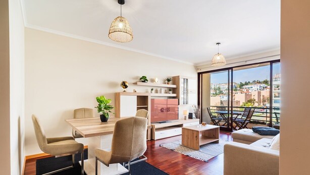 Ein modernes Wohnzimmer mit Essbereich, einer Couch, einem Couchtisch und einem Balkon mit Blick.