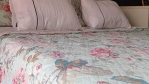 Ein Bett mit einer floralen Steude und zwei Kissen.