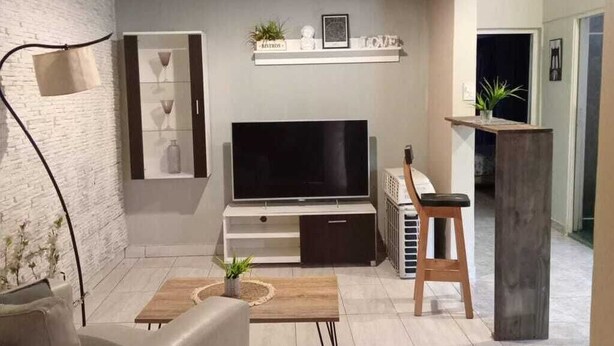Ein modernes Wohnzimmer mit Flachbildfernseher, einer Couch, einem Couchtisch und einem kleinen Hocker.