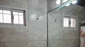 Ein Badezimmer mit Toilette, Waschbecken, Dusche und Spiegel.
