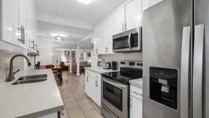 A modern kitchen with stainless steel appliances, a water dispenser, and a dining area with a table and chairs. - Garden Oasis Room near Wynwood (Miami)
