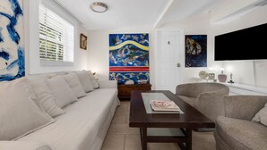 A living room with a sofa, a coffee table, and artwork on the walls. - Garden Oasis Room near Wynwood (Miami)