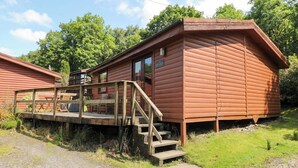 Eine Holzhütte mit einer Terrasse, Treppen und einem Schild mit der Aufschrift 'Cottage Quarters'.