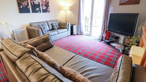 Ein Wohnzimmer mit einer Couch, einem Fernseher und einem roten Karotten Teppich.