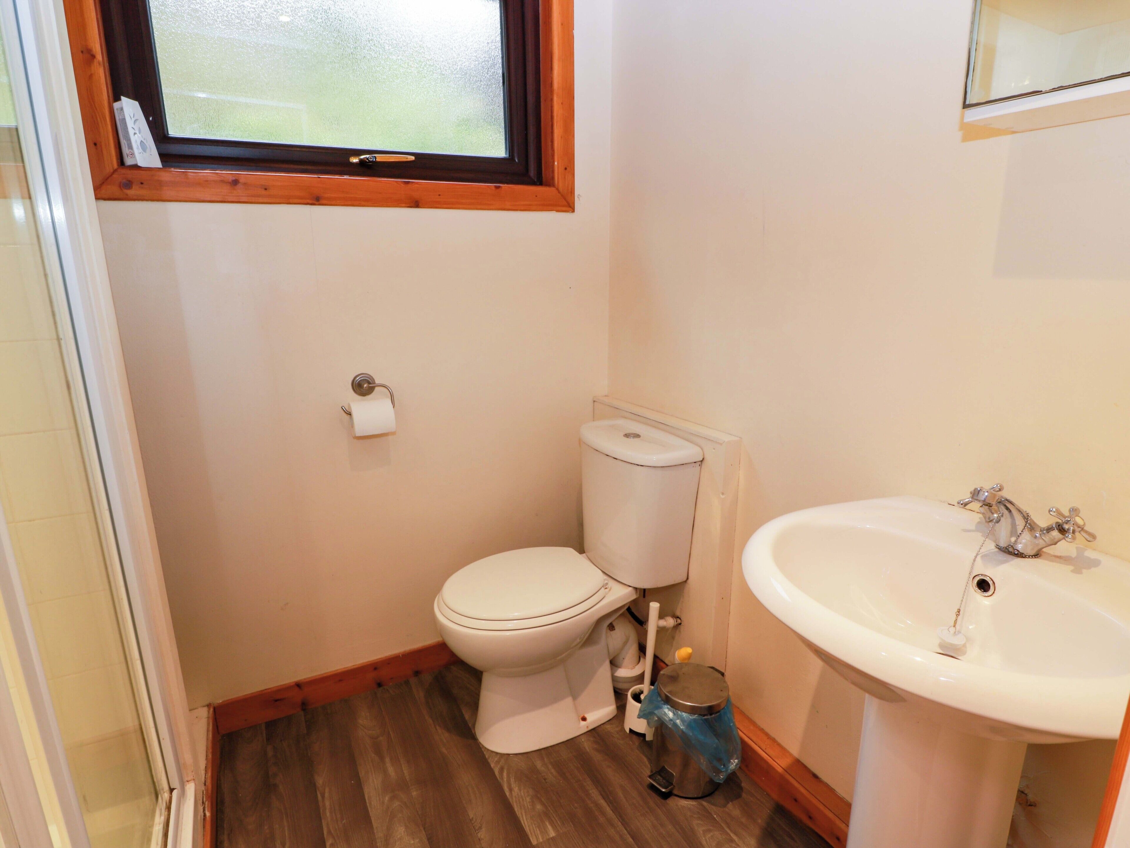 A small bathroom with a toilet, sink, and window.