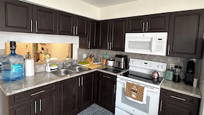 A modern kitchen with dark cabinets, a white stove, a microwave, and under-cabinet lighting. - 3bedroom-Free Parking LakeView-Sunset-Balcony-Central - 24hr Security Patrol (Homestead)