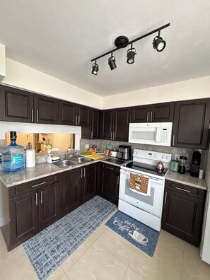 A modern kitchen with dark cabinets, a white stove, a microwave, and under-cabinet lighting.