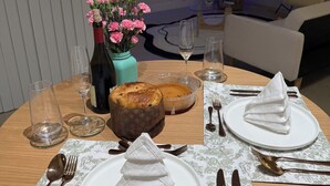 A dining table set with plates, cutlery, a cake, a vase with flowers, and a television in the background. - 3bedroom-Free Parking LakeView-Sunset-Balcony-Central - 24hr Security Patrol (Homestead)