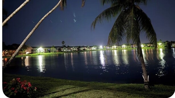 A nighttime view of a lake with palm trees and illuminated buildings in the background. - 3bedroom-Free Parking LakeView-Sunset-Balcony-Central - 24hr Security Patrol (Homestead)
