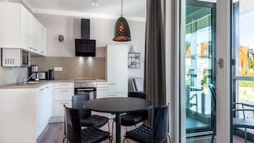 A modern kitchen with white cabinets, a black stove, and a dining area with a round table and four chairs.