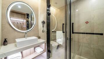 Un baño moderno con un espejo redondo, un lavabo blanco, una cabina de ducha con mampara de cristal y un perchero para toallas.