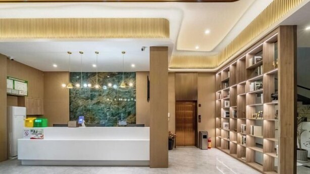 A reception area with a counter, a wall-mounted display, and a bookshelf. - Wuzhou Hotel (Pinghu)