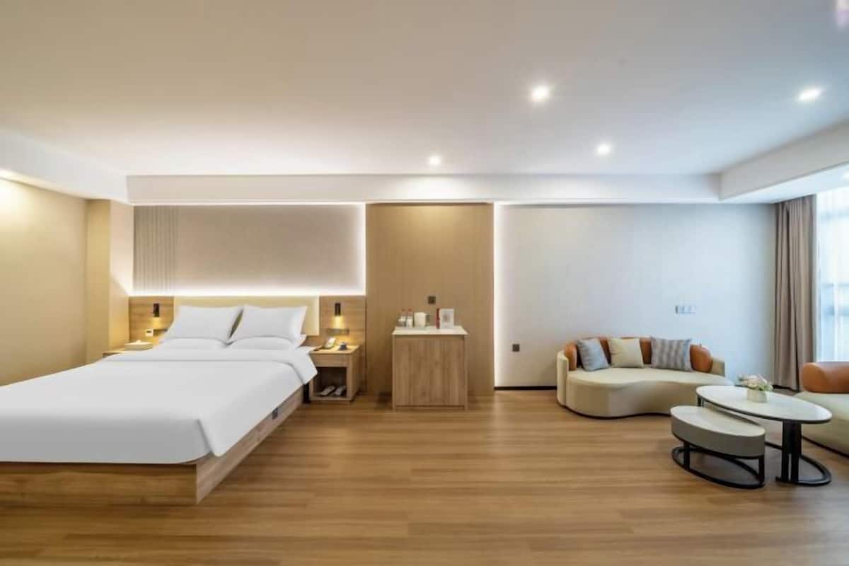 Una habitación de hotel moderna con una cama, un sofá, una mesita y una mesita de noche.