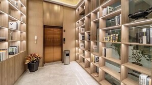 En modern hotellobby med hyllor i trä, en receptionsdisk och en krukväxt.